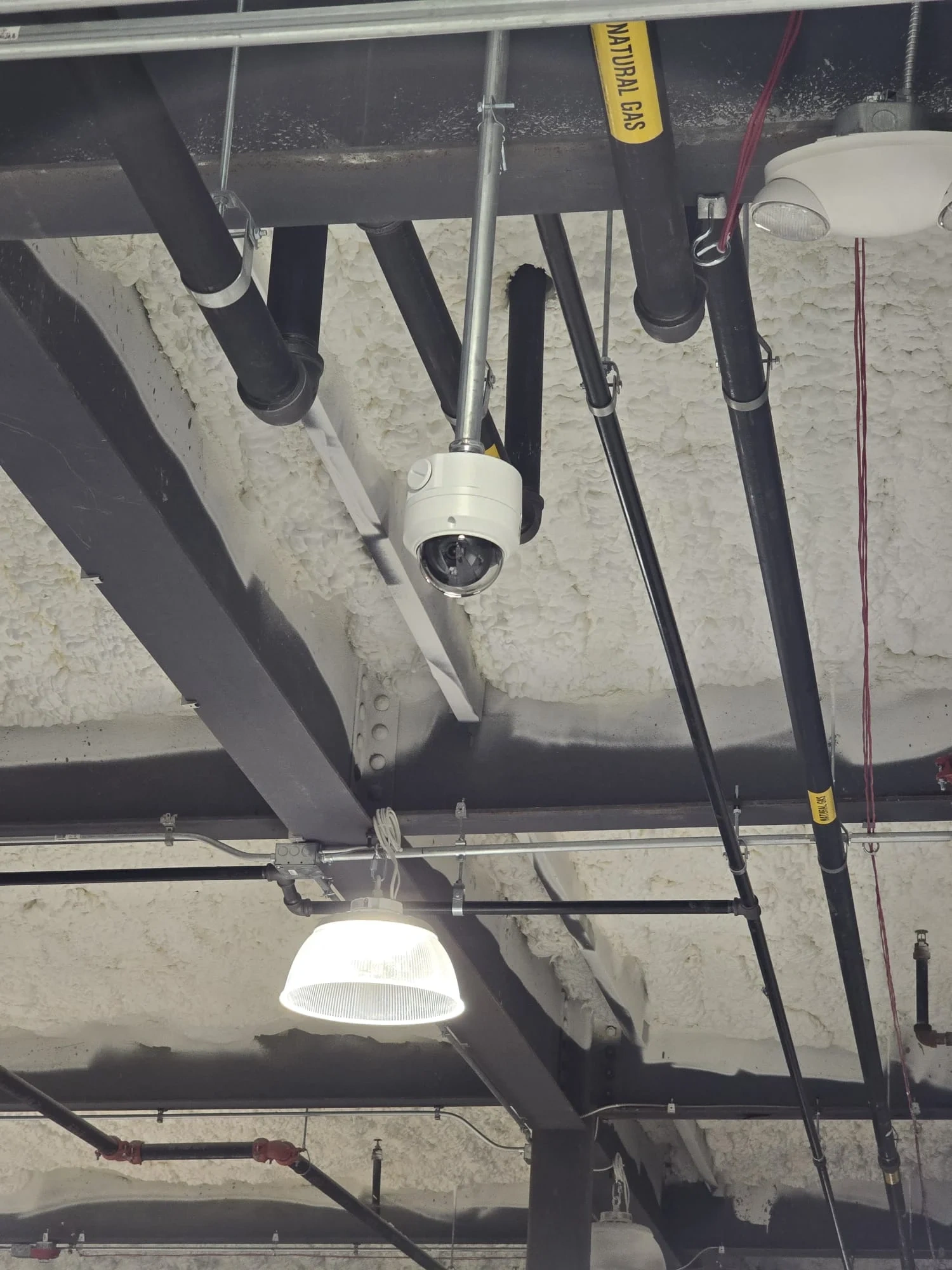 Commercial ceiling security camera installed near exposed utilities