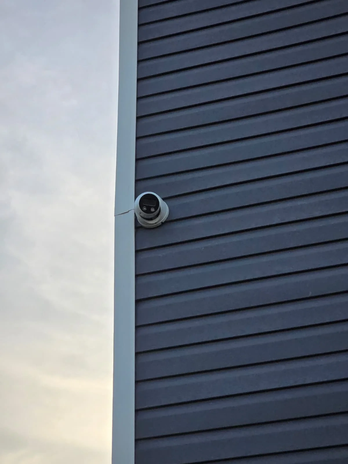 Exterior wall-mounted security camera on commercial siding
